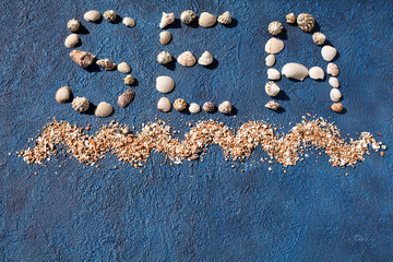 Wall Mural - Word sea made of seashells, decorative ocean wave, golden sand on blue background top view close up, summer holidays concept, sea beach vacations art design, letters made of sea shells, copy space