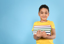 Portrait Of Cute Little Boy With Books On Color Background