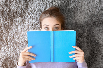 Sticker - Surprised young woman with book lying on floor, top view