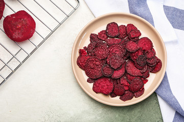 Plate with tasty beet chips on table