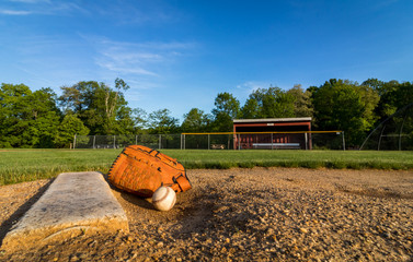 aseball and glove on pitchers mound on early morning springtime