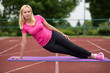 © Ewelina - Fit girl practicing stretching exercise at stadium.A girl is training on a sports field. Young beautiful girl in sports uniform posing on sports field. Fitness blonde girl doing exercises in the fresh