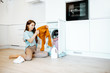 © rh2010 - Young woman sorting dirty clothes while sitting on the floor near the washing machine at home