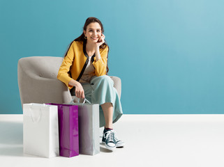 Wall Mural - Happy woman sitting on an armchair after shopping