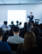 © Right 3 - 'Speaker giving a talk at a corporate business conference. Audience in hall with presenter in front of presentation screen. Blurred executive giving speech during business and entrepreneur seminar. '