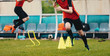 © matimix - Boy Soccer Player In Training. Boys Running Between Cones amd Jumping During Practice in Field on Sunny Day. Young Soccer Players at Speed and Agility Practice Session