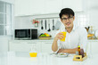 © Ann Rodchua - An asian man is drinking orange juice in the kitchen