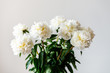 Bunch of amazing peonies in the vase on white wall background