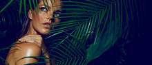 A Beautiful Tanned Girl With Natural Make-up And Wet Hair Stands In The Jungle Among Exotic Plants