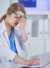 Wall Mural - Young female doctor tired after working with computer