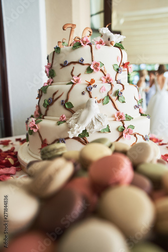 Wedding Cake With Decorative Flowers And Macarons On Candy Bar