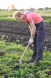 © kalinichenkod - Male farmer  with a hoe weeding in the field on sunset