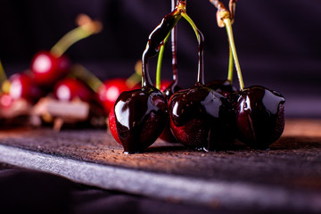 Macro close up red cherry stem, with chocolate dip fruit and frost, fresh chocolate cream decoration, on ice cream cake, with cold water drops attached, white background