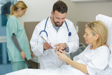 patient in hospital bed signing consent form