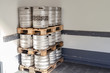 Used metal beer keg barrel on wooden pallets in corner of warehouse after delivery. Steel drink containers storage