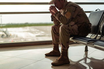 Low angle of American soldier in camouflage praying indoors