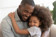 © fizkes - Loving african father hug cute child daughter with eyes closed