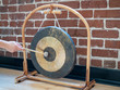 © David Tran - Small suspended gong sitting hit with mallet by hand of a woman