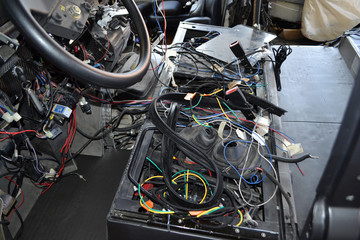 Wall Mural - A lot of ravel multicolored wires from the car wiring lies in the cabin of dismantled car with connectors and plugs, a view through the window inside the battered car. Auto service industry