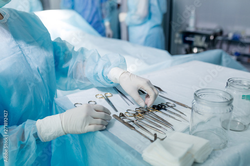 Fototapeta na szkło nurse in sterile gloves choosing tool to perform surgery. close up cropped photo.job, profession, occupation