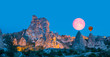 Amazing view of Uchisar castle in Cappadocia at twilight blue hour - Girls watching moonrise at the hill of Cappadocia
