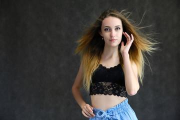 Photograph of a portrait of a beautiful girl woman with long dark flowing hair, happy life on a dark gray background. She is standing directly in front of the camera in various poses and smiling.