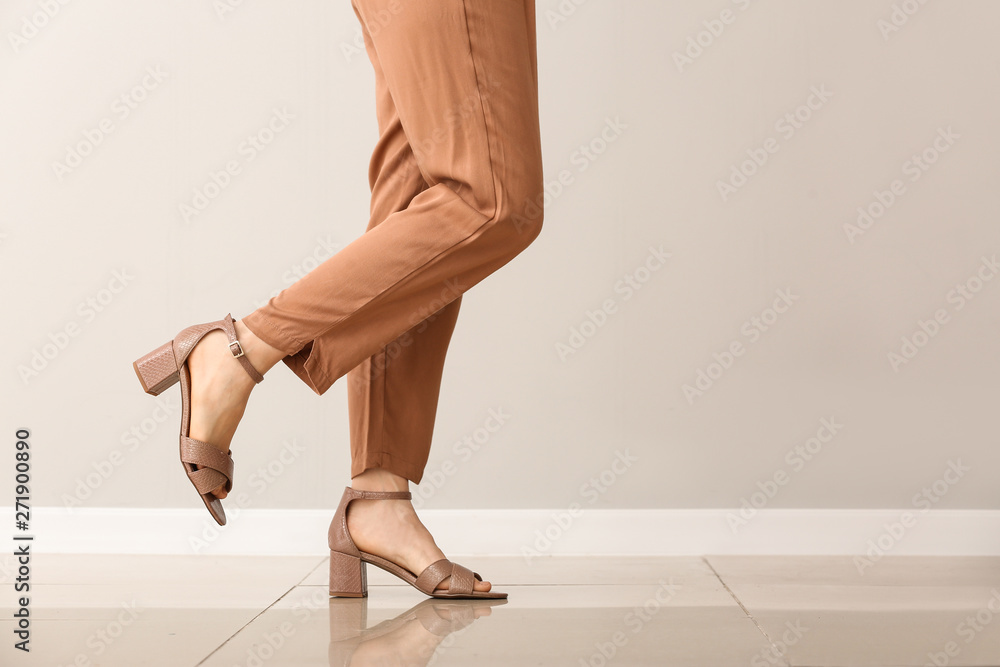 Young woman in stylish shoes against light wall