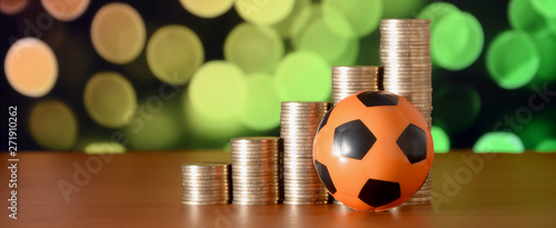 Cuadros en Lienzo Soccer ball and stacks of golden coins in growth graph on the blurred bokeh back