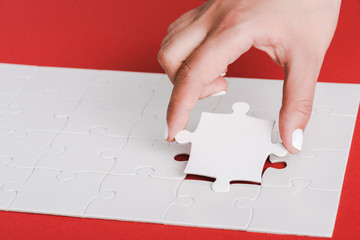 cropped of woman holding jigsaw near connected white puzzle pieces on red