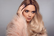 © Victoria Andreas - Blonde woman in glamorous fur coat posing in studio. Ombre blond hairstyle. Beauty fashion girl portrait. Beautiful model with makeup, long healthy hair style. Manicured nails.