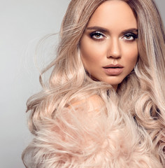 Wall Mural - Ombre blond hairstyle. Beauty fashion blonde portrait. Sexy woman wears in pink fur coat. Beautiful girl model with makeup, long healthy hair style posing isolated on studio grey background.