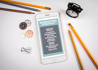 Wall Mural - marketing strategy concept. smartphone on white table. stationery and clock