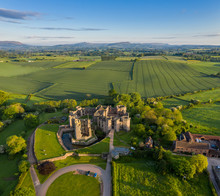 Aerial Panoramic View Of The Ruins Of Raglan Castle, A Late Medieval Castle Located Just North Of The Village Of Raglan In The County Of Monmouthshire In South East Wales, UK