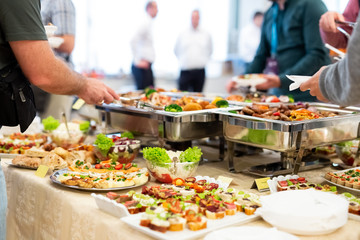 Close up of people serving themselves with canapes in buffet of restaurant.