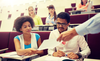 Canvas Print - education, high school, university, learning and people concept - teacher giving tests to students at lecture