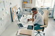 © gstockstudio - Business lifestyle. Top view of good looking young man in shirt and tie using smart phone and smiling while sitting in the office