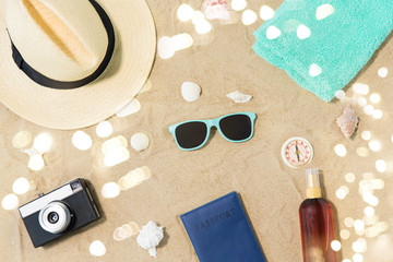 vacation, travel and tourism concept - vintage camera, passport, hat and sunglasses on beach sand