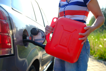 Forced stop. Ran out of gas in the tank of the car. A woman fills the car with gasoline from a spare tank. Canister of 10 liters.