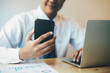 © ijeab - Young Asian startup businessman using smartphone to analyze online marketing information.