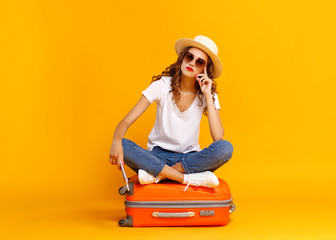 concept of travel. happy woman girl with suitcase and  passport on  yellow background.