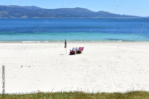 Beach With Umbrella And Empty Chairs Grass And White Sand
