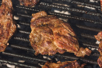 Grilling pork steaks on barbecue grill