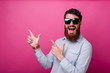 Portrait of amazed young man with beard pointing away at copyspace
