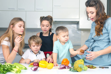 Wall Mural - mother with children preparing vegetables in the kitchen.