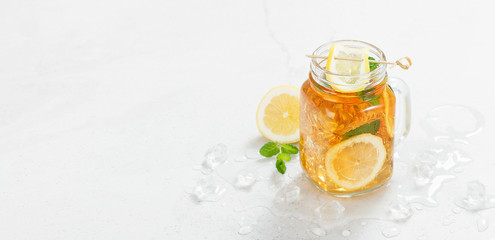 Wall Mural - Iced tea with lemon slices and mint on light gray stone background.