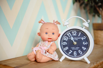 Cute doll sits on the wood background.