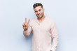 © Asier - Young handsome cool man showing victory sign and smiling broadly.