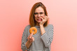 © Asier - Young woman holding a donut biting fingernails, nervous and very anxious.