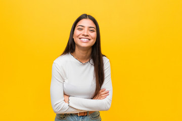 young pretty arab woman against a yellow background laughing and having fun.