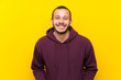 © luismolinero - Colombian man with sweatshirt over yellow wall smiling